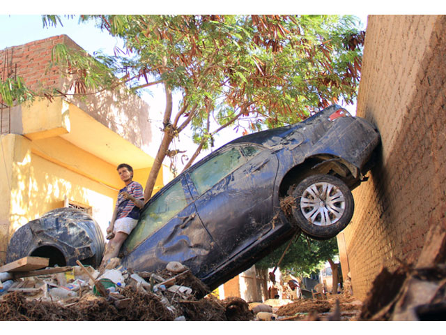 a picture taken october 29 2016 shows a boy leaning on a damaged car in ras gharib near the mouth of the gulf of suez in the red sea governorate after flooding in parts of egypt caused by torrential rains photo afp