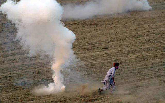 an activist of tehreek e insaf pti runs from tear gas shells during clashes with police in swabi on october 31 2016 photo afp an activist of tehreek e insaf pti runs from tear gas shells during clashes with police in swabi on october 31 2016 photo afp