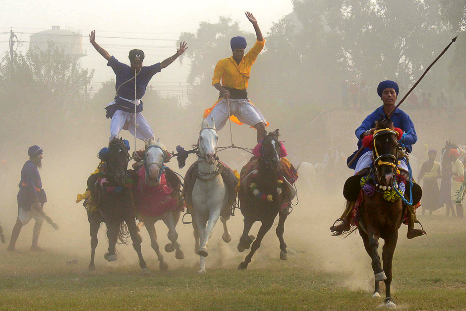 two members of the indian sikh 039 nihang 039   the traditional sikh army   balance on four horses as they demonstrate their skills during a fateh divas celebration which takes place the day after the diwali festival in amritsar photo afp