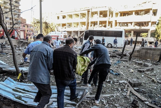rescue officials and people carry an injured man at the explosion site on november 4 2016 after a strong blast in the southeastern turkish city of diyarbakir at least one person was killed and 30 injured in a blast outside a police building on november 4 in diyarbakir photo afp