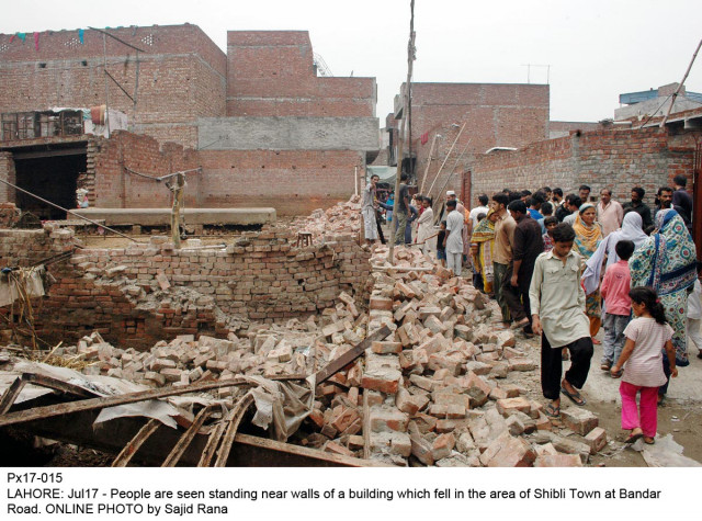 people are seen standing near walls of a building which fell in the area of shibli town of lahore on sunday photo online people are seen standing near walls of a building which fell in the area of shibli town of lahore on sunday photo online