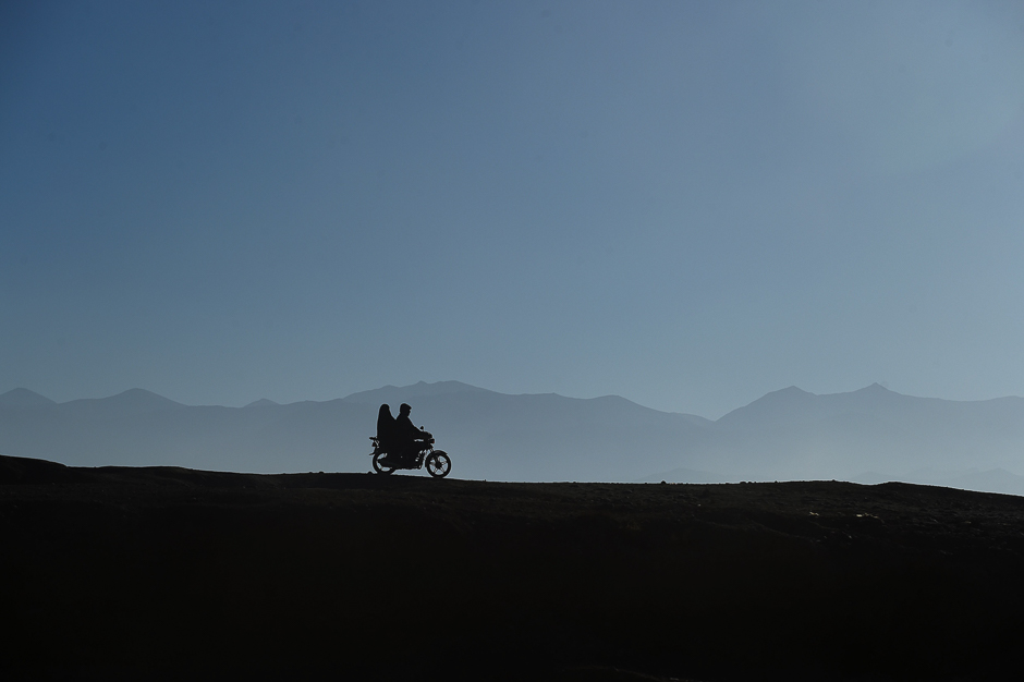 afghan passengers ride a motorcycle along a road in bamiyan photo afp