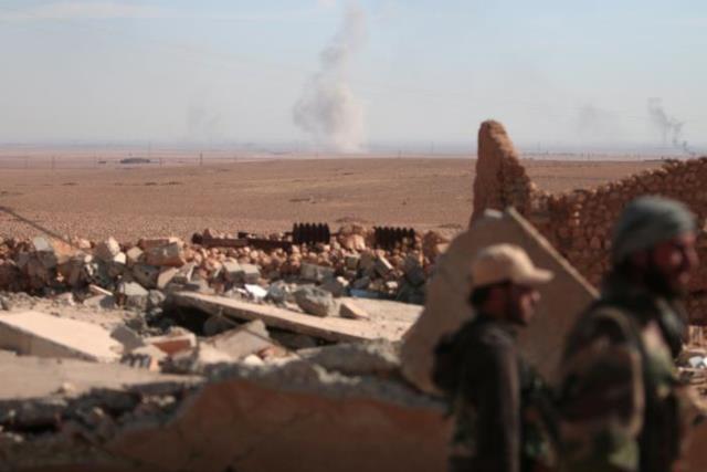 smoke rises in the background as syrian democratic forces sdf fighters stand near rubble of a destroyed building north of raqqa city syria november 7 2016 photo reuters