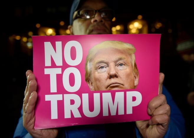 a man holds a placard at an anti racism protest against us president elect donald trump outside of the us embassy in london photo reuters