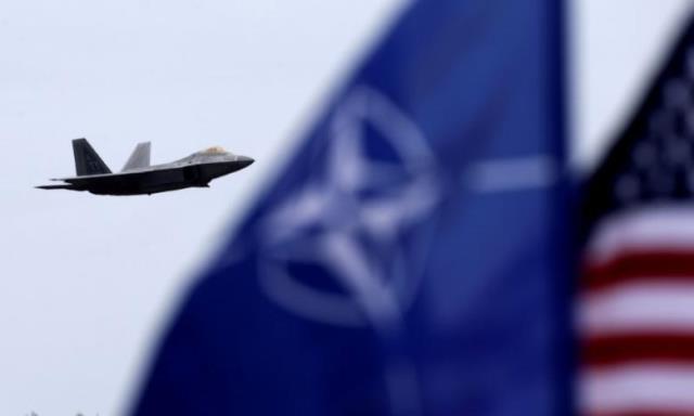 nato and u s flags flutter as u s air force f 22 raptor fighter flies over the military air base in siauliai lithuania april 27 2016 photo reuters