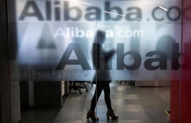 an employee is seen behind a glass wall with the logo of alibaba at the company 039 s headquarters on the outskirts of hangzhou zhejiang province april 23 2014 photo reuters