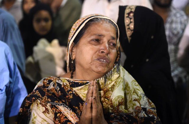 a woman prays for a relative in karachi on november 12 2016 following a bombing at a sufi shrine in khuzdar balochistan photo afp