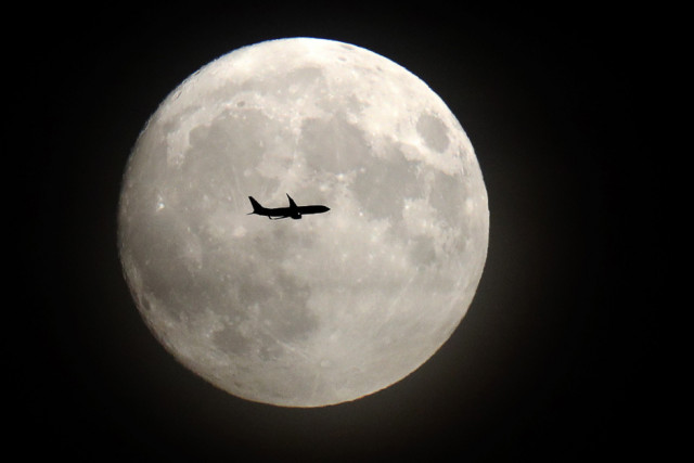 a commerical jet flies in front of the moon on its approach to heathrow airport in west london photo afp a commerical jet flies in front of the moon on its approach to heathrow airport in west london photo afp