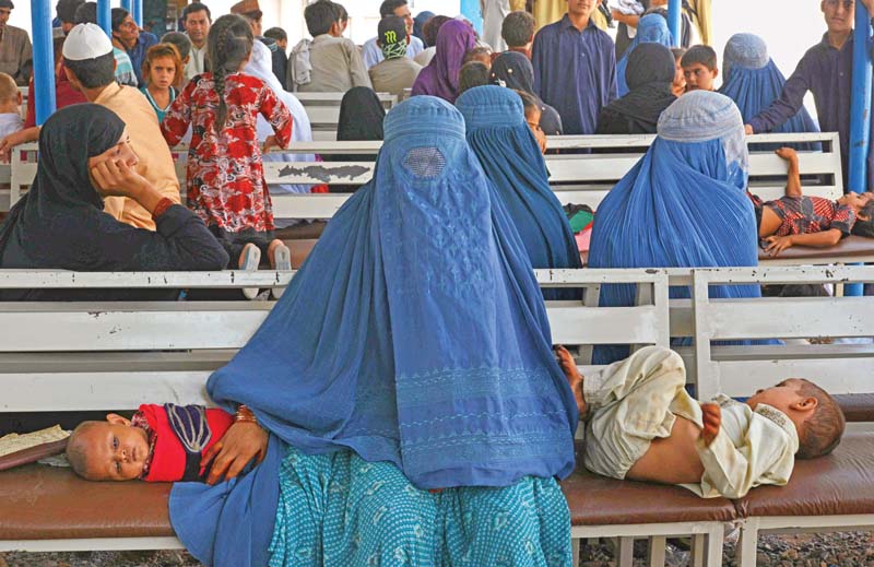 an afghan refugee woman waits with her children to register at the unhcr office photo file