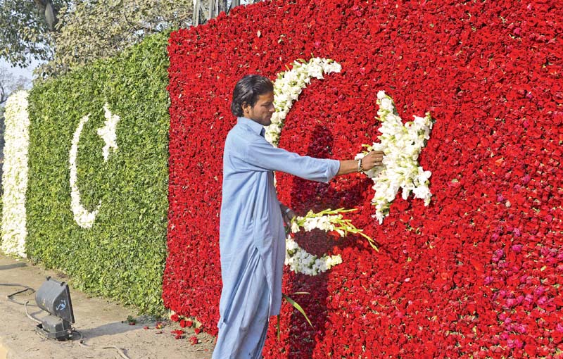 a worker makes the star of the turkish flag with flowers below people cheer as the turkish president s car travels through lahore photos afp amp abid nawaz