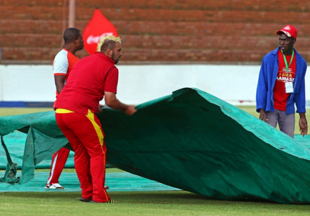 groundstaff cover the ground with a tarpaulin after rain delayed the fourth tri nation one day international odi cricket match between zimbabwe and west indies at queens sports club in bulawayo on november 21 2016 photo afp