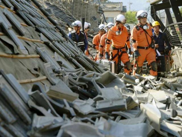 firefighters walk among collapsed houses caused by an earthquake in southern japan photo reuters