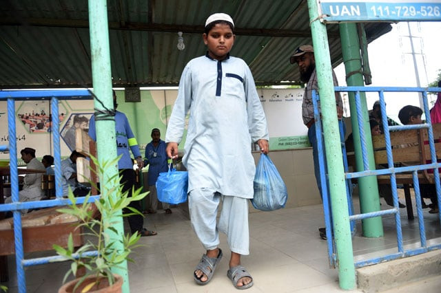 shah nawaz 14 leaves a donation centre with food for his family members in karachi photo afp shah nawaz 14 leaves a donation centre with food for his family members in karachi photo afp