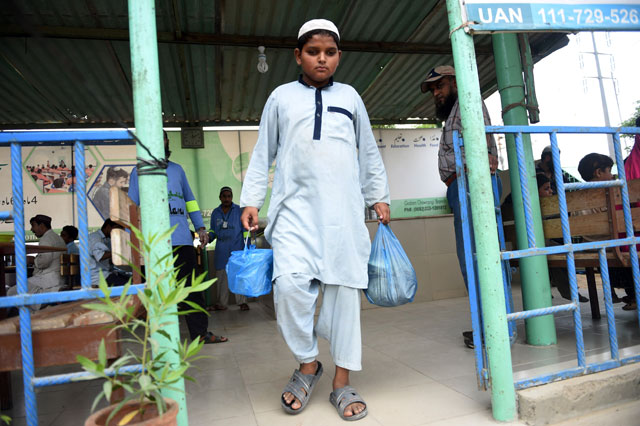 shah nawaz 14 leaves a donation centre with food for his family members in karachi photo afp
