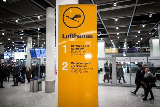 flight passengers walk past an information sign with the logo of german airline lufthansa on november 25 2016 at the airport in duesseldorf western germany photo afp