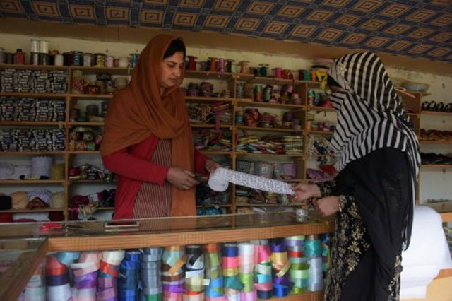 pakistani kashmiri sara rasheed l sells border trim cloth to a customer at her shop in the women 039 s market on the outskirts of the town of rawalakot photo afp