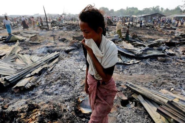 a woman walks among debris after fire destroyed shelters at a camp for internally displaced rohingya photo reuters