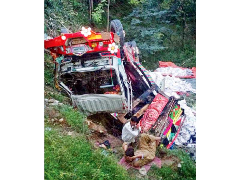 two men sit next to a truck that fell in a ravine in abbottabad killing three persons on board and leaving five others injured photo online