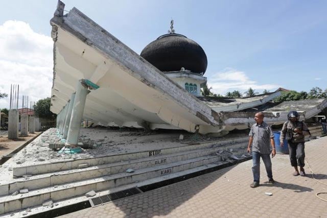 people walk near a collapsed mosque following an earthquake in meuredu pidie jaya in the northern province of aceh indonesia december 7 2016 in this photo taken by antara foto photo reuters