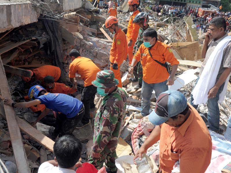 members of a search and rescue team look for survivors trapped in rubble in pidie jaya photo afp