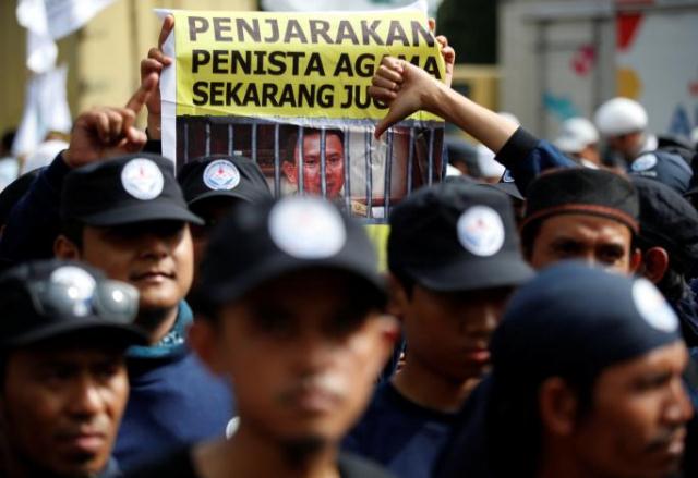 a protester holds a banner outside a court during the first day of the blasphemy trial of jakarta 039 s governor basuki tjahaja purnama also known as ahok in jakarta indonesia december 13 2016 photo reuters