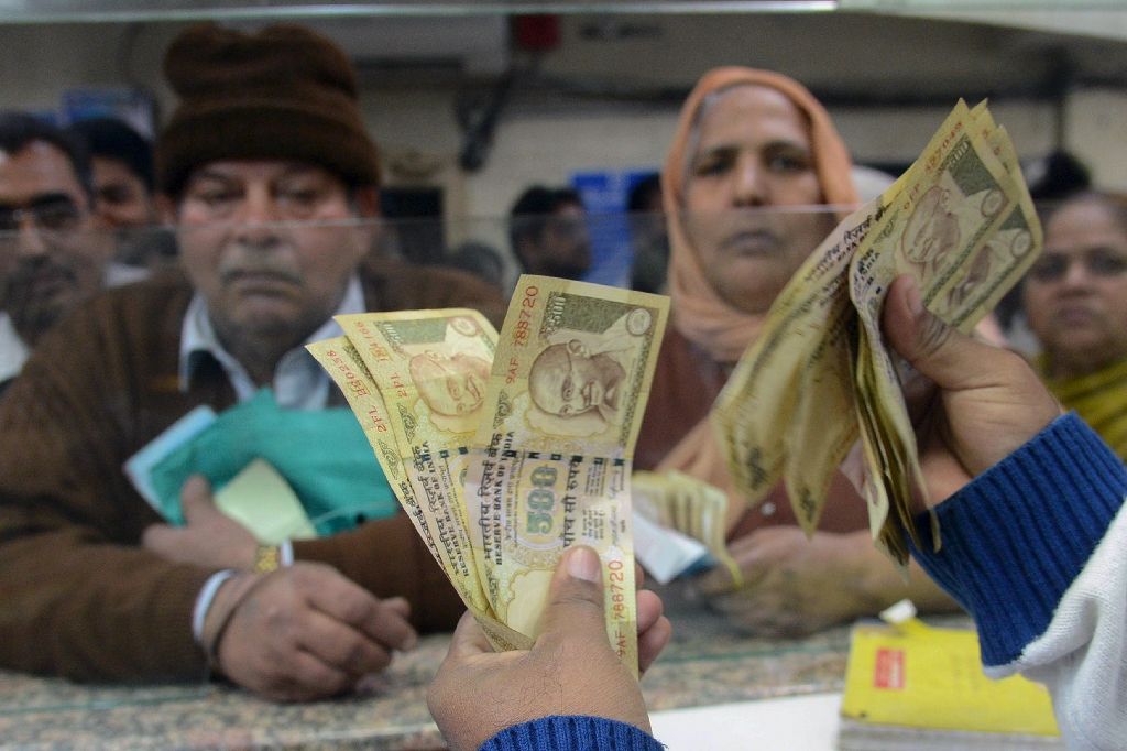 an indian bank teller counts out notes as senior citizens deposit and exchange 500 and 1000 rupee notes in amritsar on november 19 2016 photo afp