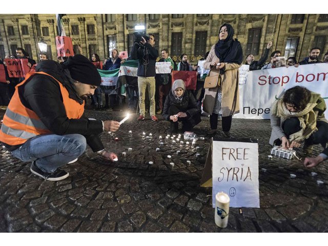 people light candles in tribute to the victims of the syrian city of aleppo during a vigil on dam square in amsterdam on december 14 2016 photo afp