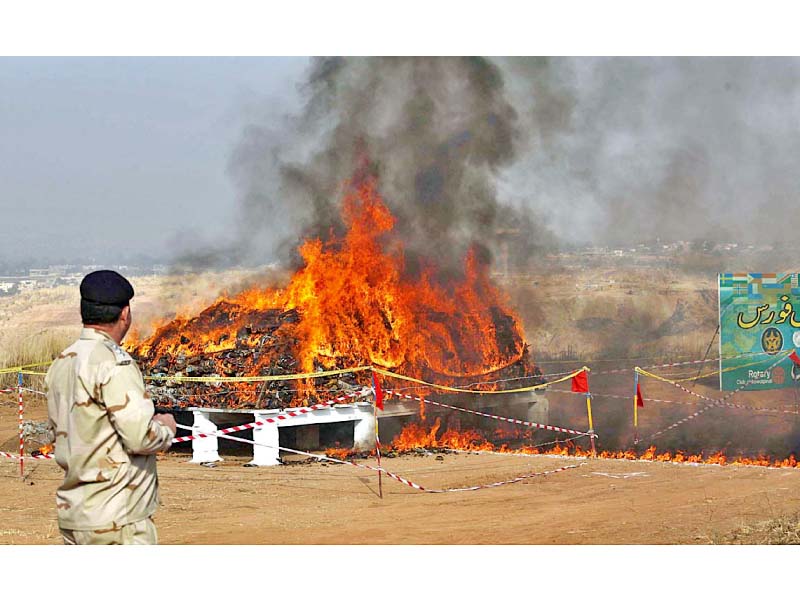 a security official stands near the dump of narcotics put to the torch by the anf in rawalpindi photo app