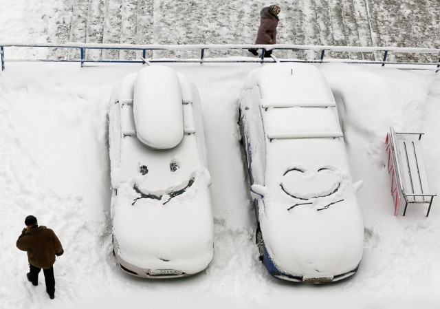 people walk past cars with faces which are scrawled on windscreens covered with snow after snowfall in krasnoyarsk siberia russia december 1 2016 photo reuters