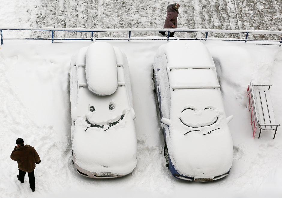 people walk past cars with faces which are scrawled on windscreens covered with snow after snowfall in krasnoyarsk siberia russia december 1 2016 photo reuters