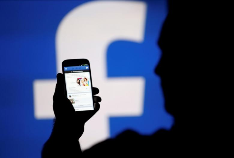 a man is silhouetted against a video screen with a facebook logo as he poses with a samsung s4 smartphone in this photo illustration taken in the central bosnian town of zenica august 14 2013 photo reuters