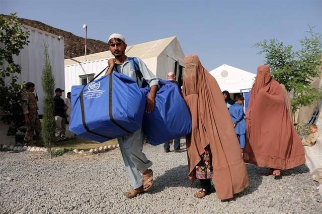 an afghan family who were living as refugees in pakistan carries bundles of supplies at a humanitarian aid station in torkham afghanistan photo reuters