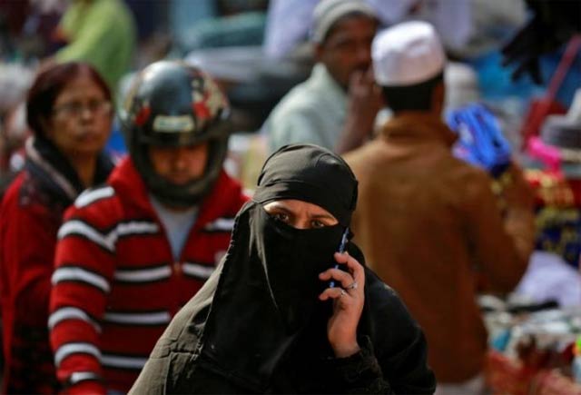 a muslim woman speaks on her mobile phone as she walks through a market in delhi photo reuters