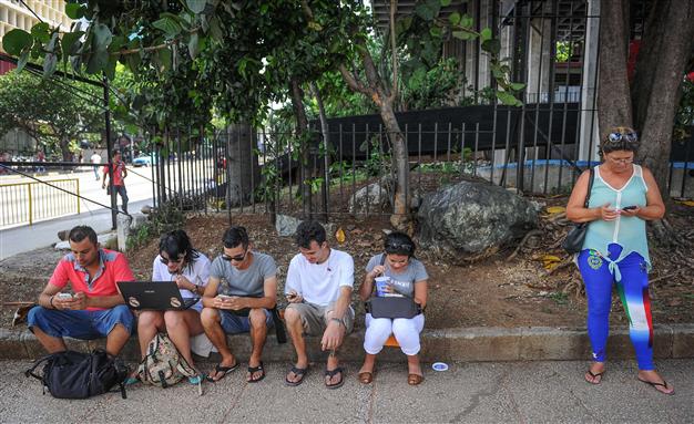 cubans use their mobile devices to connect to internet via wi fi in a street of havana on july 2 2015 photo afp