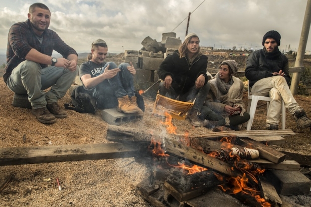 young israeli settlers gather around a fire in the settlement outpost of amona which was established in 1997 and built on private palestinian land in the israeli occupied west bank on december 18 2016 photo afp