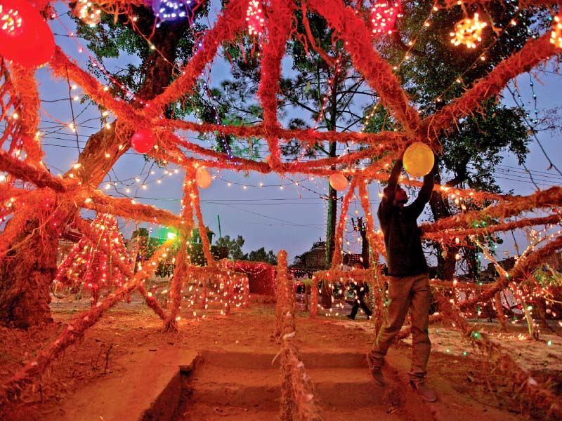 a man puts up coloured lights in a christian neighbourhood on the eve of christmas in islamabad photo reuters