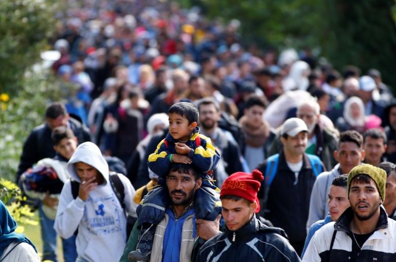 a migrant carries a child on his shoulders as they walk to cross the border with austria in hegyeshalom hungary photo reuters