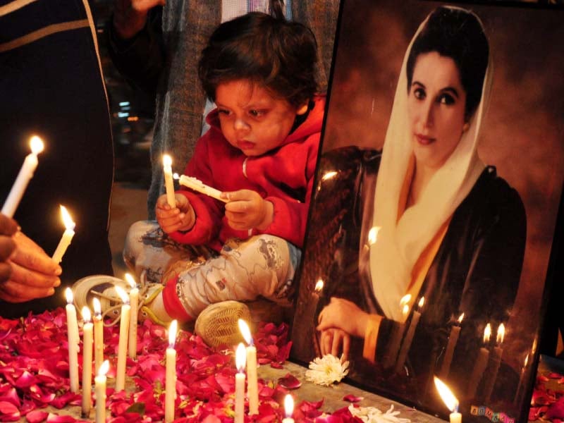 a child lights a candle at a vigil organised on mall road photo express