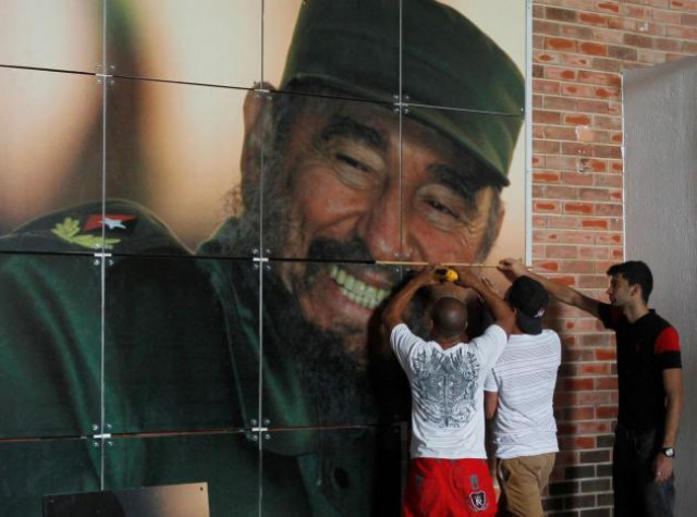 workers install a photograph of cuba 039 s former president fidel castro at the expocuba exhibition center photo reuters