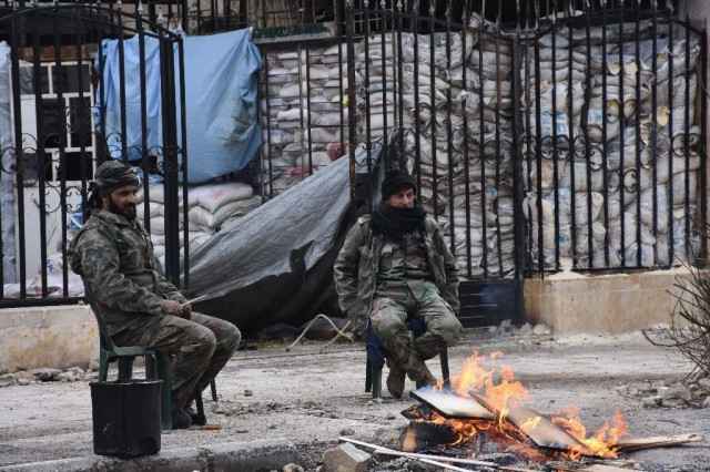 syrians soldiers sit by a fire in the former rebel held ansari district of aleppo on december 23 2016 photo afp