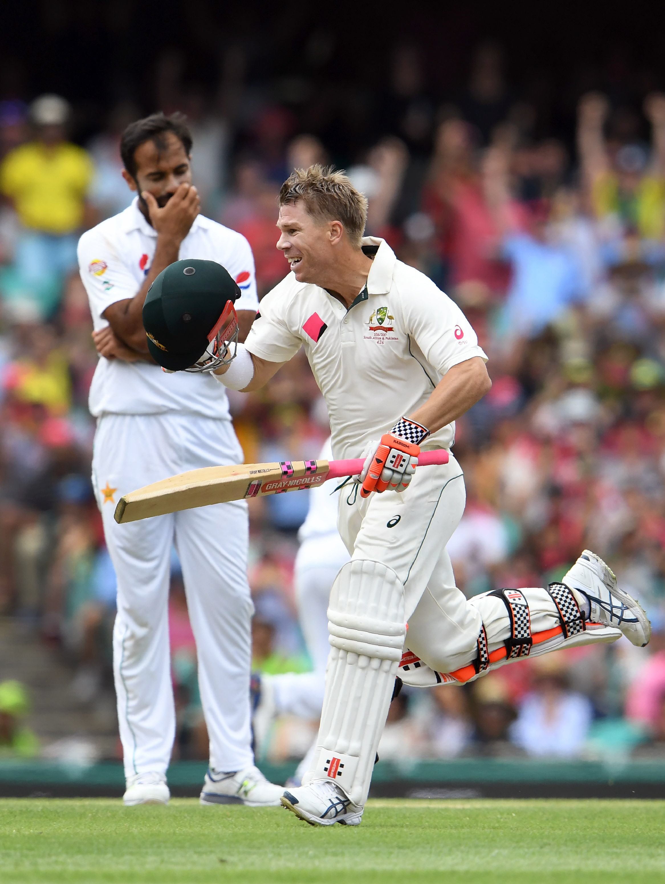 david warner celebrates scoring a century as wahab riaz l looks on at the scg on january 3 2017 photo afp