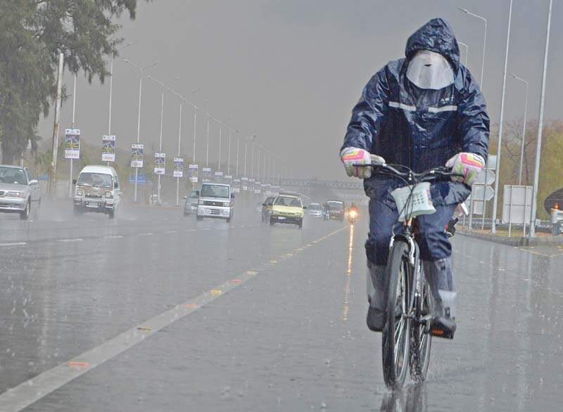 a cyclist pedals along the islamabad highway during rain photo mudassar raja express