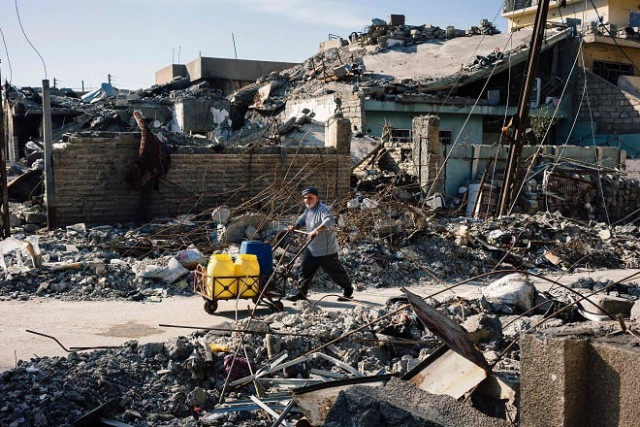an iraqi man pushes cart with cans of water between ruined buildings in mosul 039 s qadisiyah neighbourhood on january 11 2017 photo afp an iraqi man pushes cart with cans of water between ruined buildings in mosul 039 s qadisiyah neighbourhood on january 11 2017 photo afp