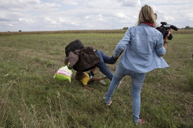 a migrant carrying a child falls after being tripped over by tv camerawoman petra laszlo r while trying to escape from a collection point in roszke village hungary september 8 2015 photo afp a migrant carrying a child falls after being tripped over by tv camerawoman petra laszlo r while trying to escape from a collection point in roszke village hungary september 8 2015 photo afp