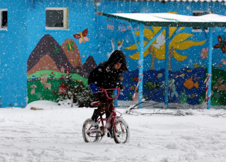 a stranded refugee boy rides his bicycle through a snowstorm at a refugee camp north of athens january 10 2017 photo reuters