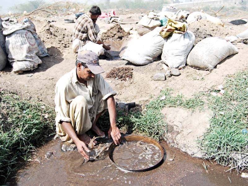 a 2012 photo in which a man filters sand on the lyari river bed photo file