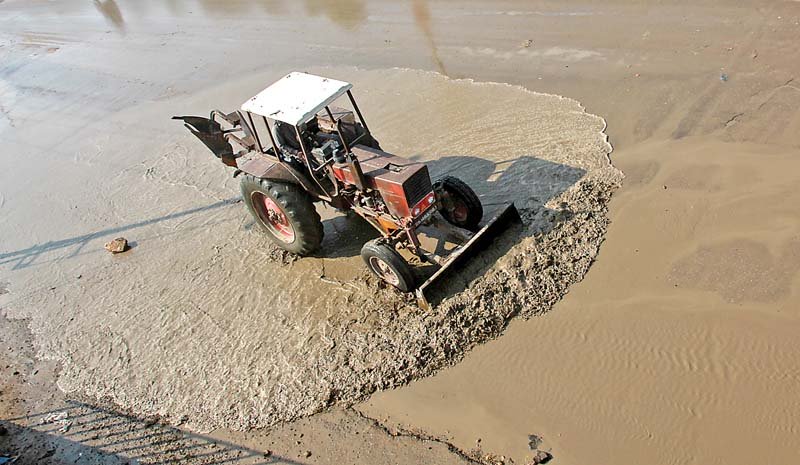 a tractor trying to dispense and evaporate the water accumulated on university road in the aftermath of first winter rains accumulation of garbage and pools of rain water worsened the sanitation and traffic condition in the city photo athar khan express