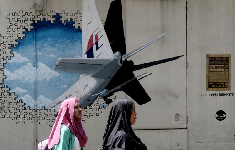 women walk past a mural depicting the missing malaysia airlines mh370 plane in shah alam malaysia photo afp