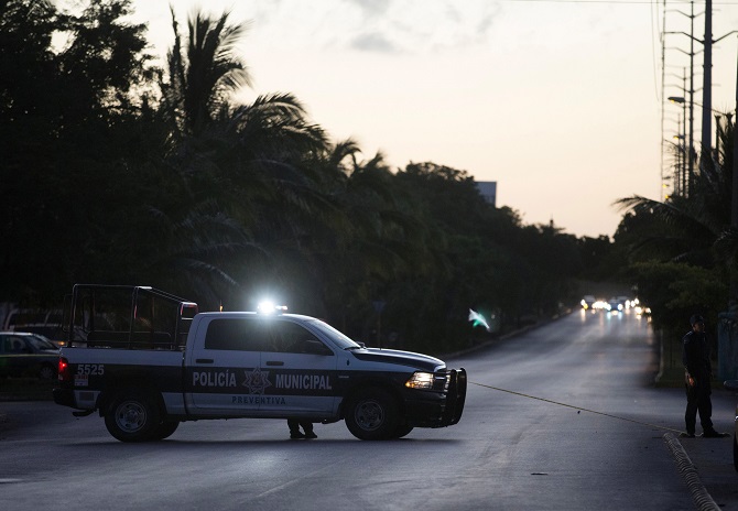 a car of the municipal police blocks the street after an armed group of men driving past on motorcycles shot at the attorney general 039 s office according to local media in cancun mexico january 17 2017 photo reuters