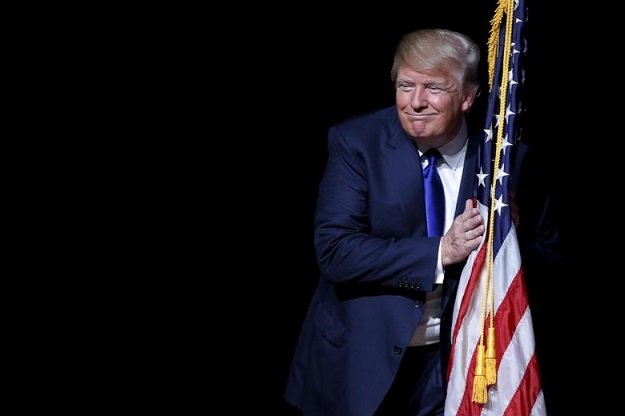 republican presidential candidate donald trump hugs a us flag as he takes the stage for a campaign town hall meeting in derry new hampshire august 19 2015 photo reuters